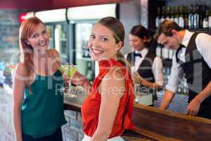 Portrait of friends holding a cocktail in front of bar counter