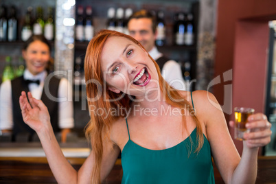 Portrait of drunk woman with tequila shot laughing in front of counter
