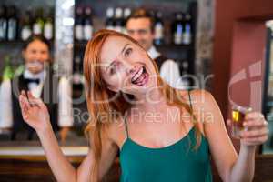 Portrait of drunk woman with tequila shot laughing in front of counter
