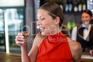 Happy woman holding a tequila shot in front of bar counter