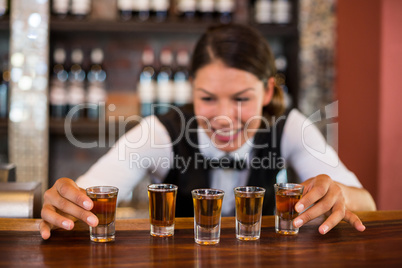 Bartender placing shot glasses on bar counter