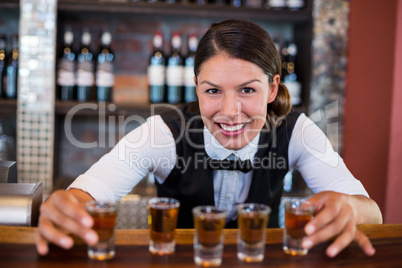 Portrait of bartender placing shot glasses on bar counter
