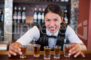Portrait of bartender placing shot glasses on bar counter