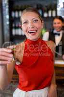 Portrait of happy woman holding a tequila shot in front of bar counter