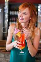 Happy woman holding a cocktail glass at bar counter