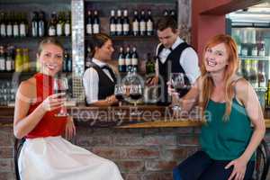 Portrait of happy woman holding a red wine glass at bar counter