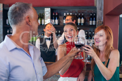 Friends toasting with a glass of red wine in a bar