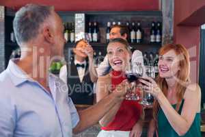Friends toasting with a glass of red wine in a bar
