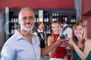 Portrait of friends toasting with a glass of red wine in a bar