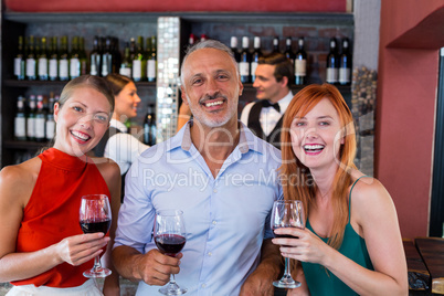 Portrait of friends standing at bar counter with a glass of red wine