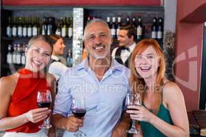 Portrait of friends standing at bar counter with a glass of red wine