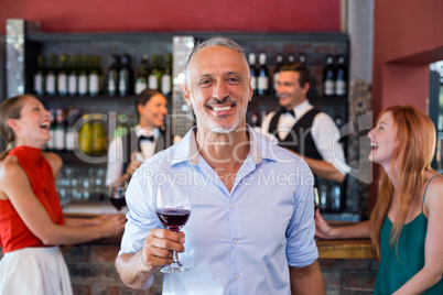Portrait of man holding a wine glass in front of bar counter