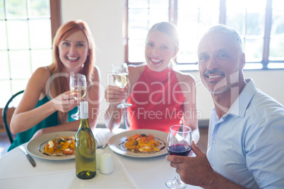 Friends holding wine glass while having meal