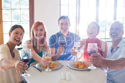 Friends showing wine glass while having meal