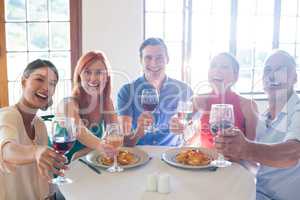 Friends showing wine glass while having meal