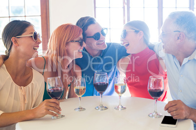 Group of friends in sunglasses laughing in restaurant
