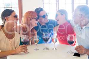 Group of friends in sunglasses laughing in restaurant
