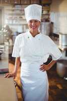 Portrait of happy chef standing with hand on hip