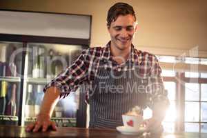 Smiling waiter holding a coffee cup at counter
