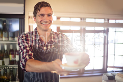 Waiter serving cup of coffee at counter