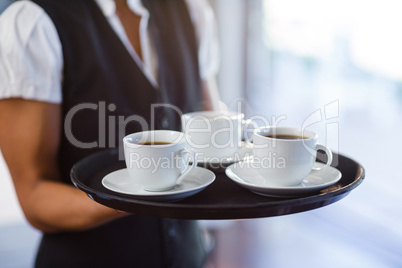 Mid section of waitress holding a tray of coffee cups