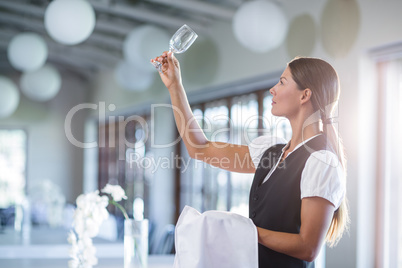 Smiling waitress holding up a empty wine glass