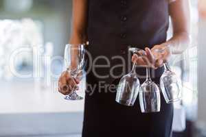 Mid section of waitress holding empty wine glasses