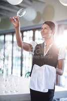 Smiling waitress holding up a empty wine glass