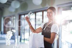 Smiling waitress holding up a empty wine glass