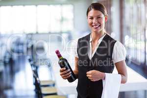 Waitress holding a bottle of red wine and a napkin