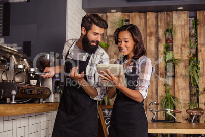 Waitress using a tablet computer and waiter with coffee machine