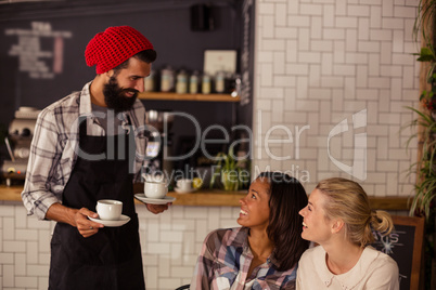 Waiter serving coffee and interacting with customers
