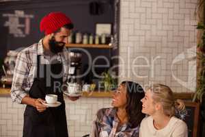 Waiter serving coffee and interacting with customers