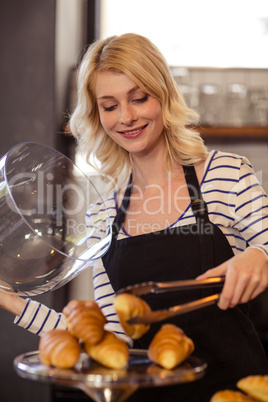 Seller picking a croissant with tongs