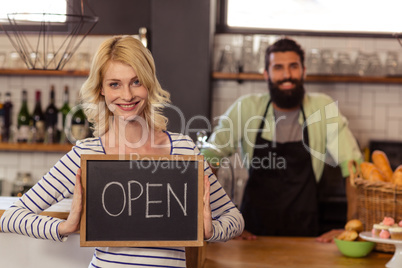 Portrait of two casual waiters holding a board written open