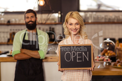 Portrait of two waiters holding a board written open