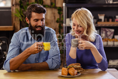 Couple eating croissant and drinking coffee
