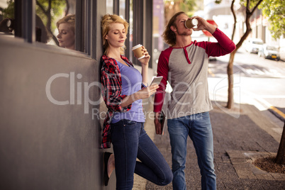Customers using a smartphone and drinking coffee