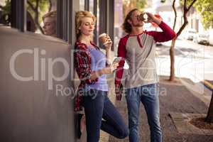 Customers using a smartphone and drinking coffee