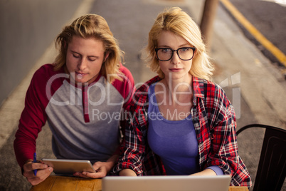 Couple using a laptop and a tablet computer on an outdoor terrace