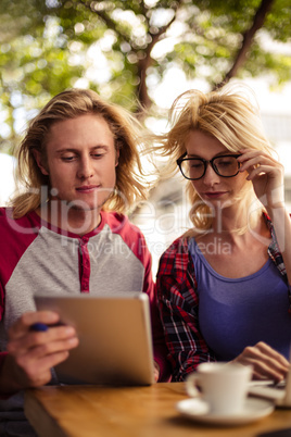 Couple using a tablet computer on an outdoor terrace