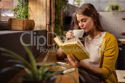 Casual woman reading a book while drinking