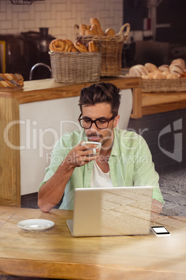Hipster using a laptop while drinking coffee