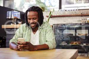 Young man using mobile phone in cafeteria