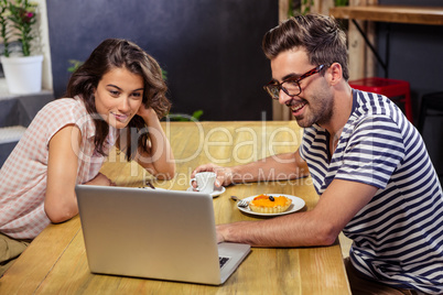 Young couple using laptop in cafeteria