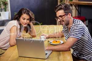 Young couple using laptop in cafeteria