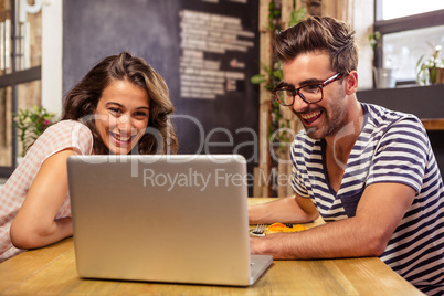 Young couple using laptop in cafeteria