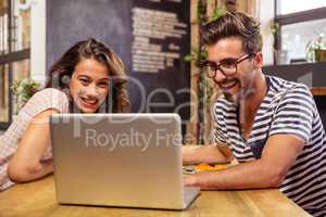 Young couple using laptop in cafeteria