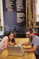 Young couple using laptop in cafeteria