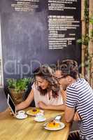 Young couple using digital tablet in cafeteria